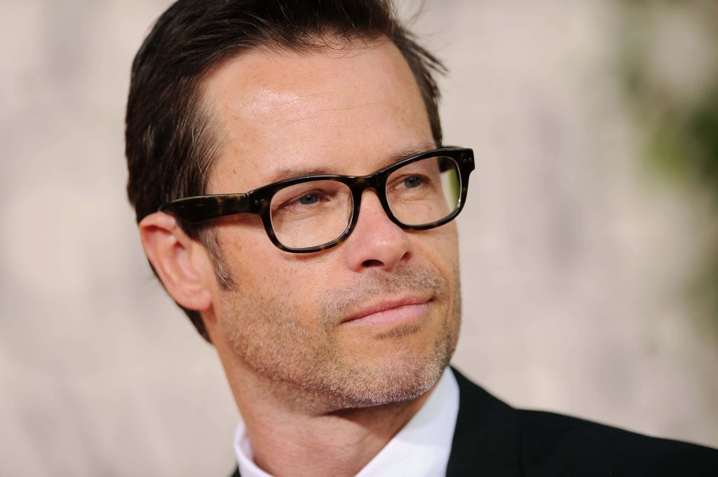 High-resolution portrait of Guy Pearce in tortoiseshell glasses and formal suit jacket Wallpaper