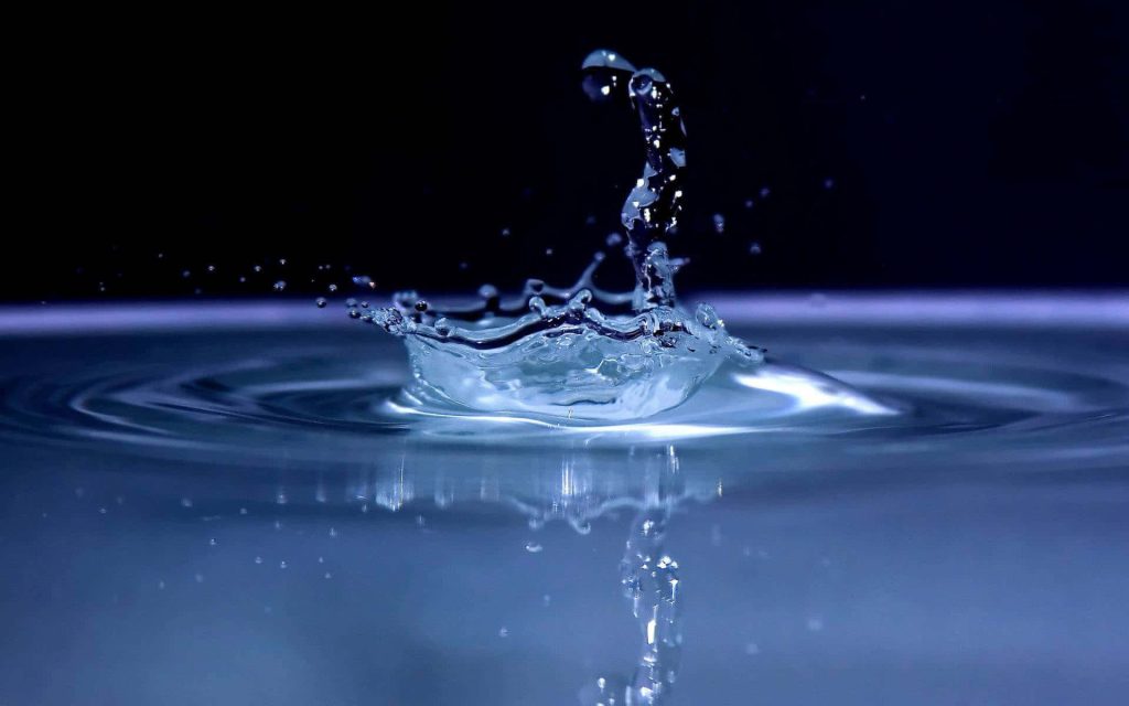 High-speed macro photo of blue water drop crown splash with ripples on black background wallpaper