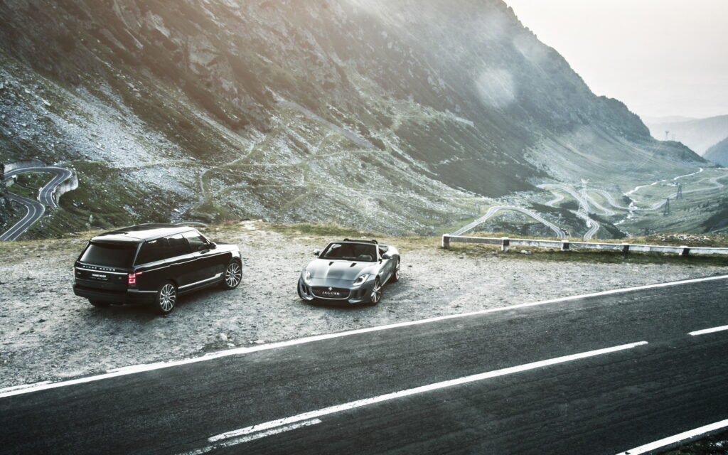 Sleek Jaguar F-Type & Range Rover: Luxury on Scenic Mountain Road Wallpaper