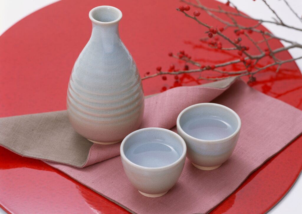 Elegant Japanese Tableware: Ceramic Sake Set on Vibrant Red Tray Wallpaper