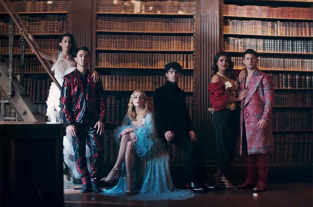 Elegant Jonas Brothers and Wives in Luxurious Library Wallpaper
