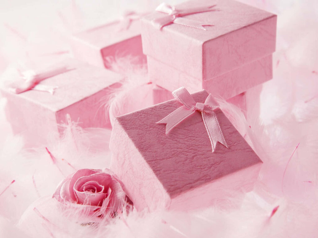 Elegant pink gift boxes with ribbons surrounded by feathers and a soft pink rose background Wallpaper