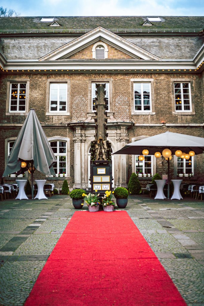 Red carpet in historic brick courtyard lit by warm lanterns festive elegant wallpaper background