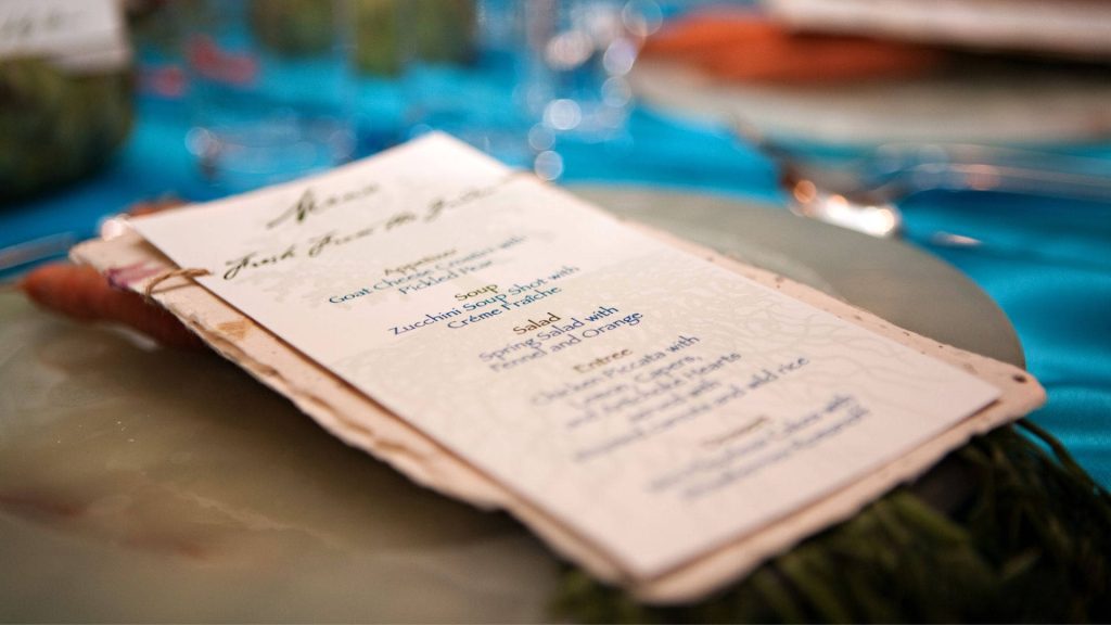 Rustic deckled-edge wedding menu on vibrant turquoise table with soft cinematic bokeh background Wallpaper