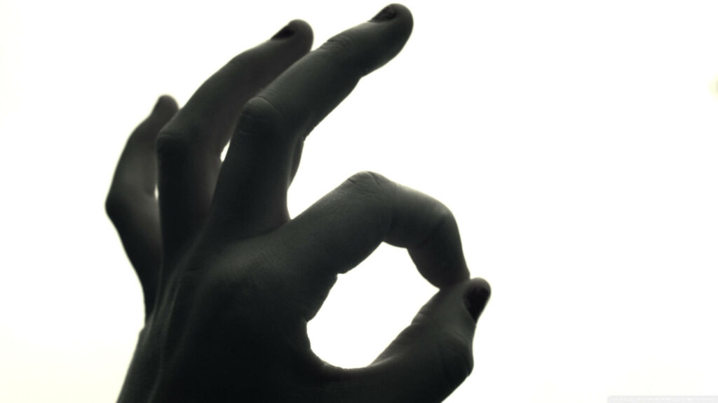 Striking Silhouette: Okay Sign Hand Wallpaper Against Bright Background