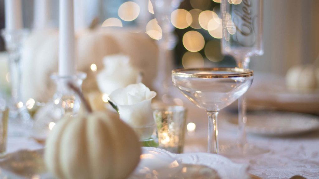Elegant Thanksgiving centerpiece with white pumpkins roses crystal glassware and warm lights Wallpaper