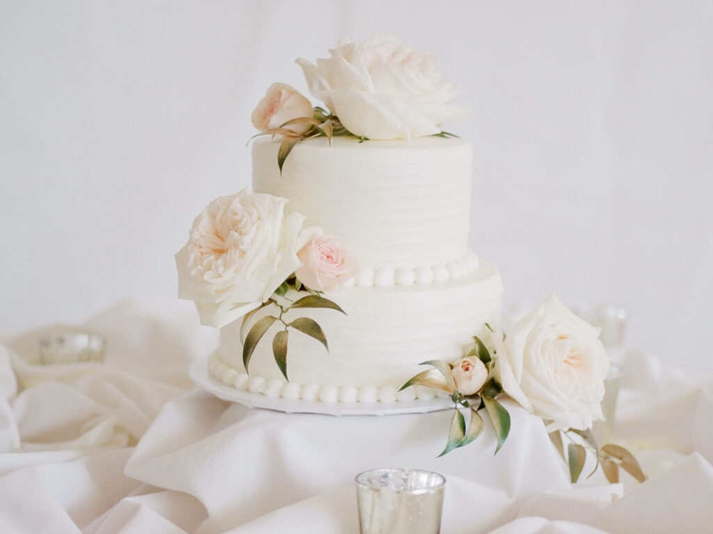 Two-tiered wedding cake wallpaper with white pink roses green leaves and smooth buttercream texture
