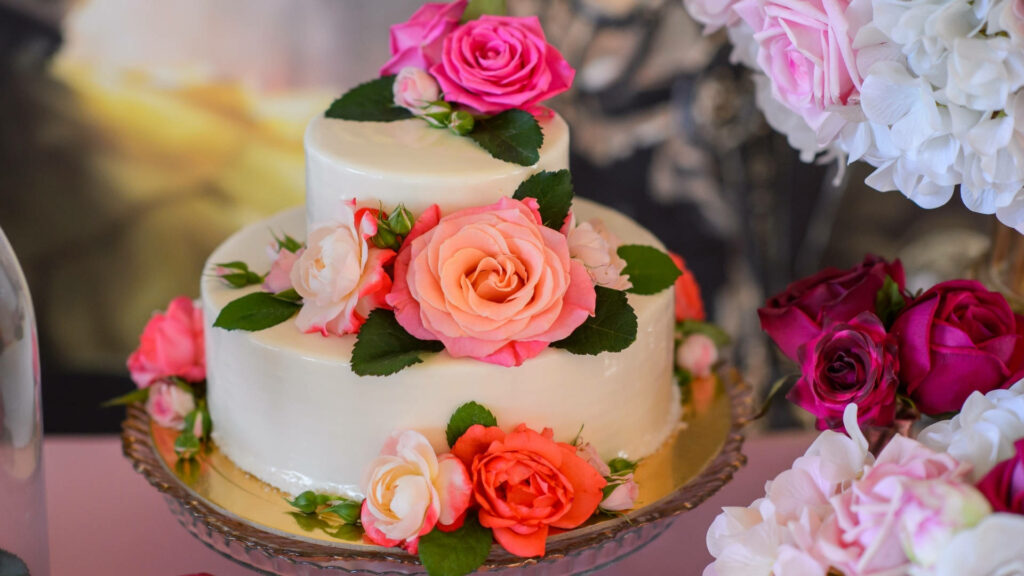 Elegant wedding cake wallpaper adorned with red and pink roses on romantic soft backdrop
