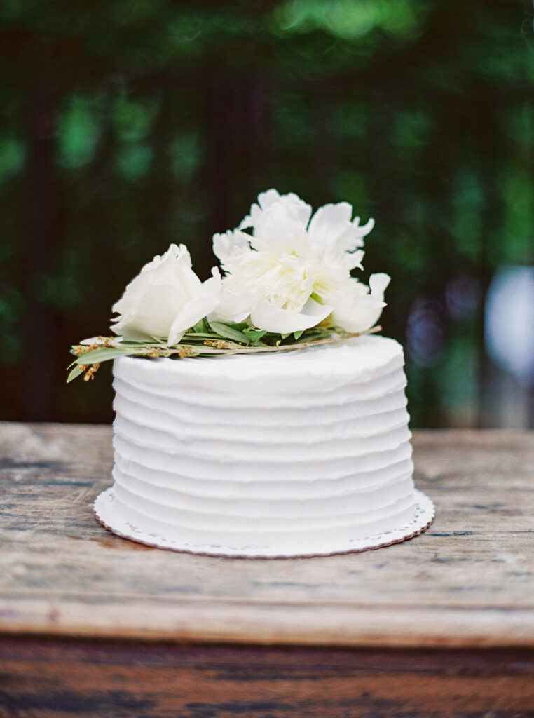 Elegant wedding cake with real white roses and textured icing on rustic wooden table background Wallpaper