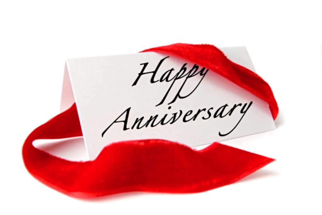White anniversary card with black text and red ribbon on festive wallpaper background