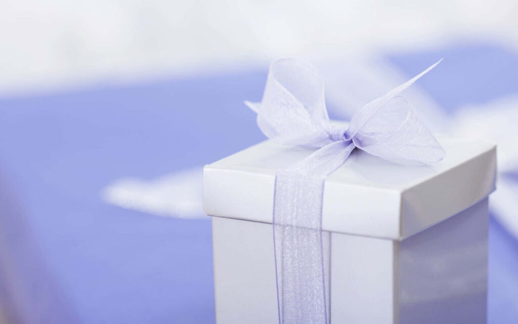 White gift box with sheer lavender ribbon on pastel background celebrating special occasions Wallpaper