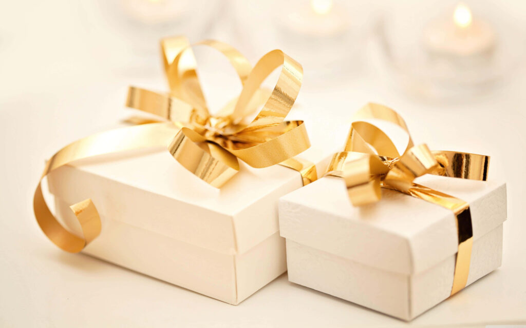 Two elegant white gift boxes with gold ribbons on wallpaper background for luxury celebration