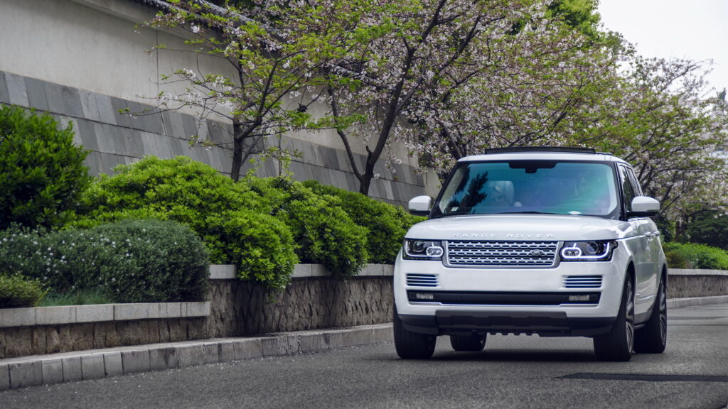 Elegant White Range Rover SUV on Scenic Tree-Lined Street Wallpaper