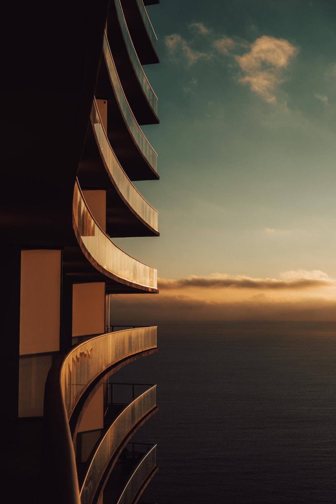 Elegant iPhone wallpaper with sleek curved glass balconies and sunset over tranquil ocean view