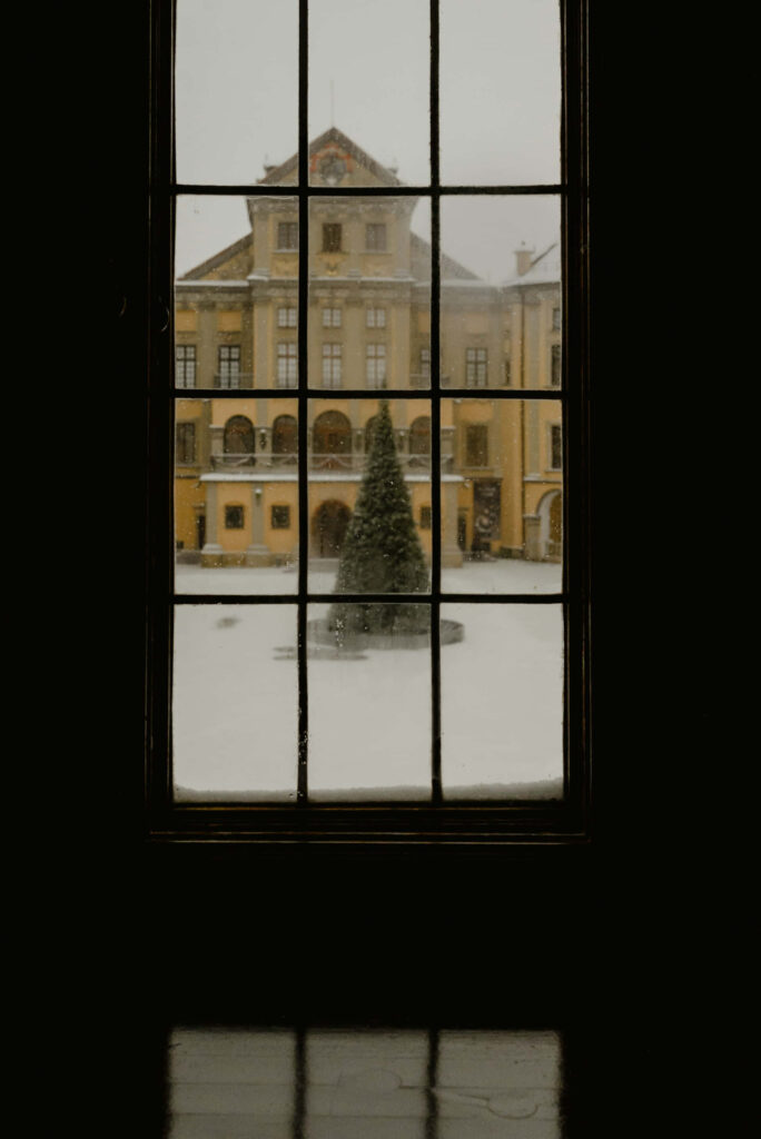 Serene Winter View: Grand Estate Framed by Window with Snowy Courtyard Wallpaper