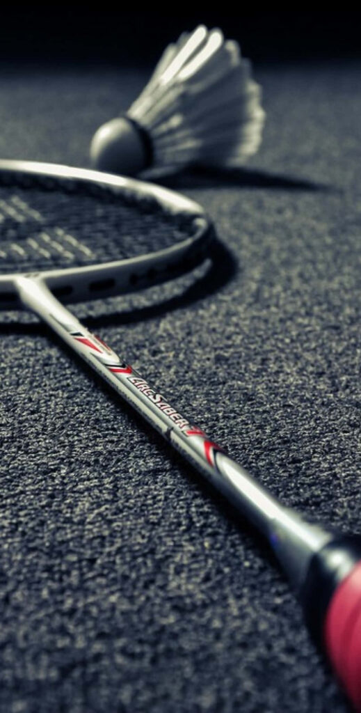 The Dance of Precision: A Striking Badminton Racket with Shuttlecock on Concrete Ground Wallpaper