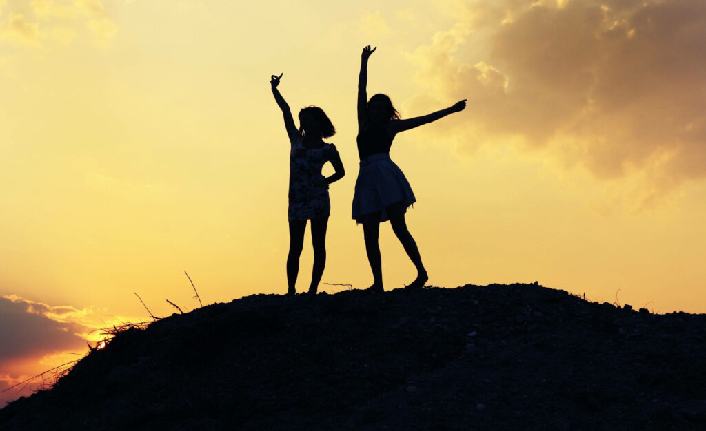 Basking in Friendship's Glow: Adorable BFFs Embrace the Golden Horizon Wallpaper