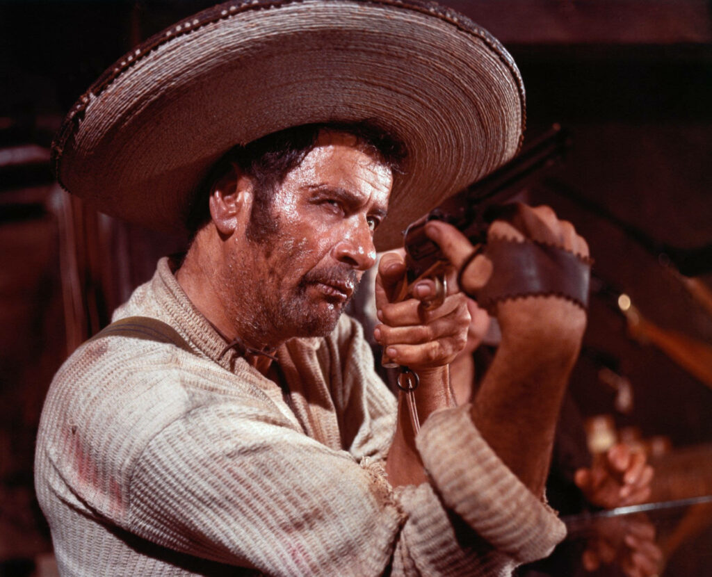 Eli Wallach aiming rifle in vintage Western scene with dramatic lighting and rugged textures wallpaper
