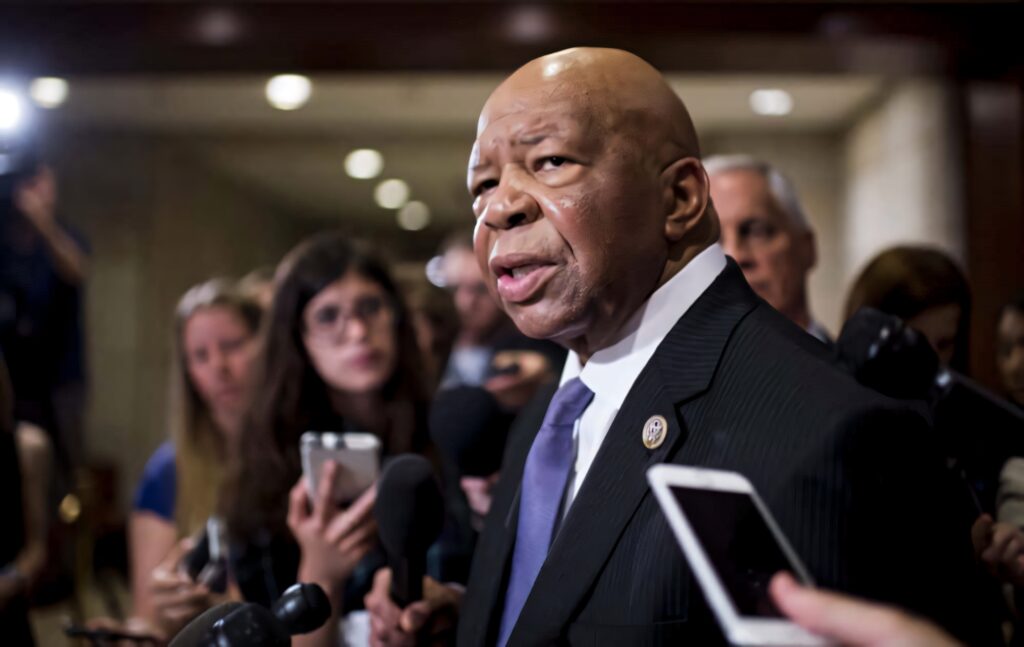 Elijah Cummings in formal suit speaking to reporters in hallway with cameras and microphones Wallpaper