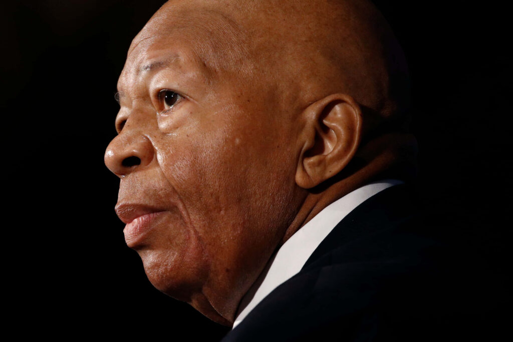 Close-up profile of Elijah Cummings with thoughtful expression on dark textured wallpaper background