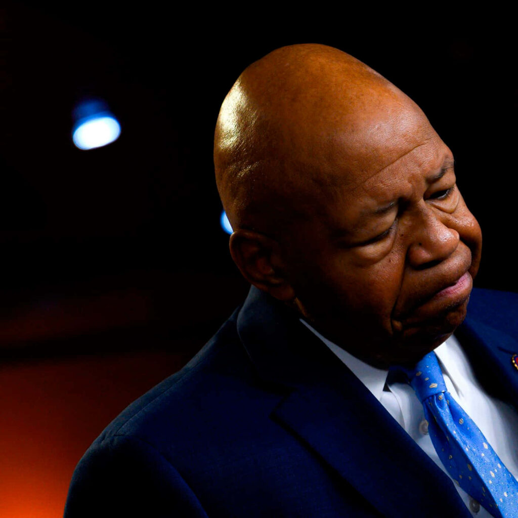 Elijah Cummings in blue suit deep in thought with warm lighting and blurred background wallpaper