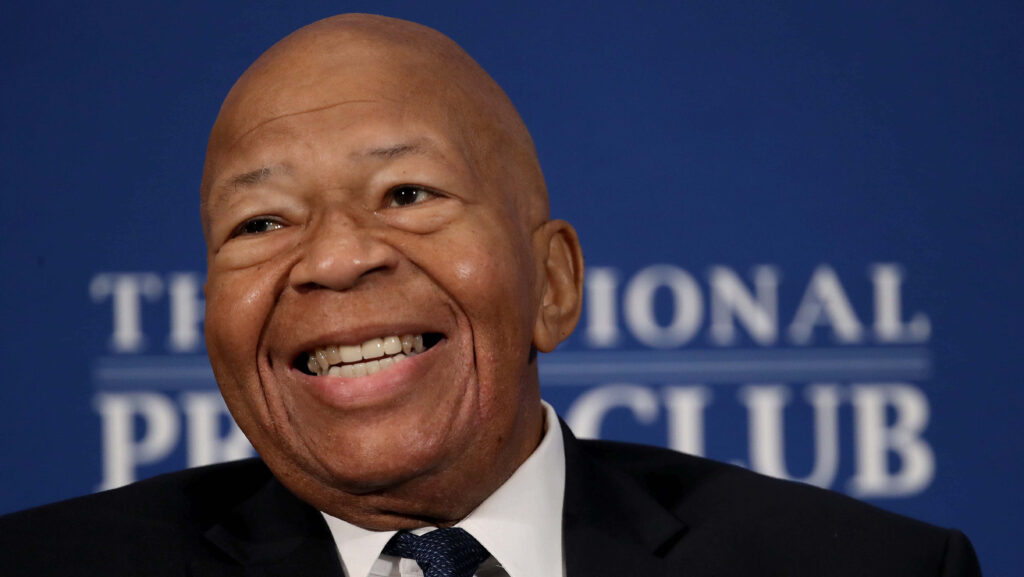 Elijah Cummings smiling warmly with dignified presence on deep blue wallpaper background