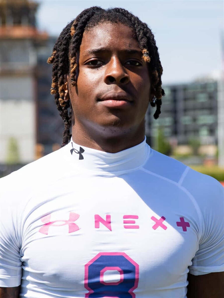 Elijah Moore confident athlete portrait in white Under Armour shirt with pink blue accents urban background Wallpaper