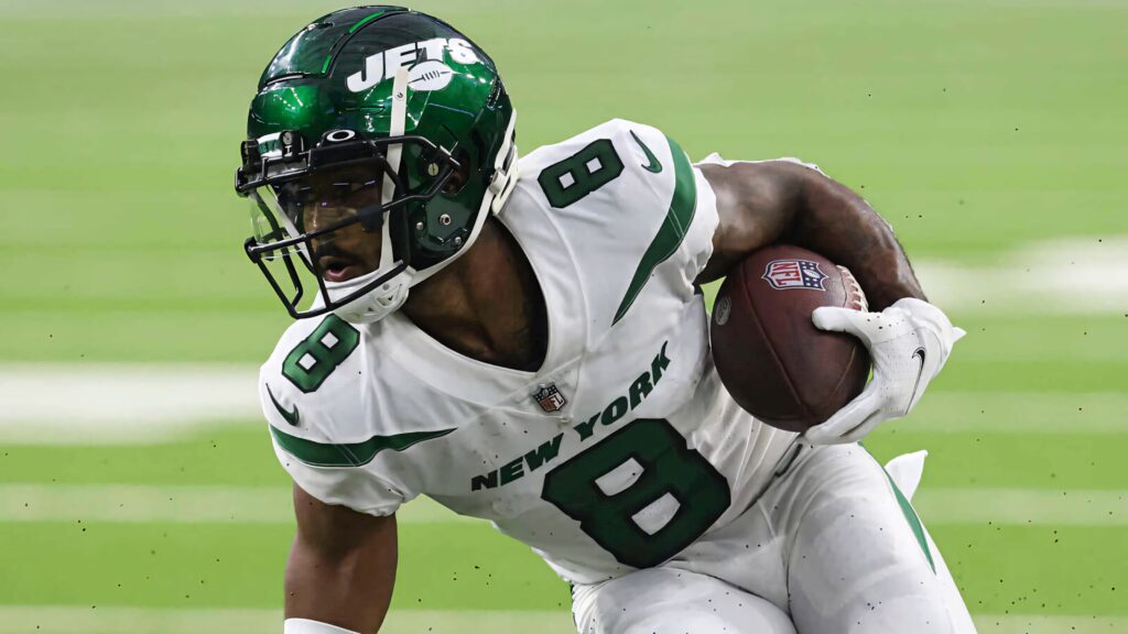 Elijah Moore New York Jets in white and green uniform mid-action on blurred NFL field background Wallpaper