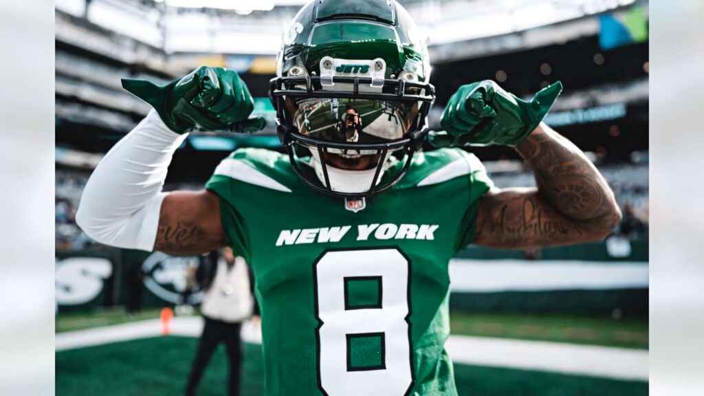 Elijah Moore New York Jets celebrating on field green uniform game day energy stadium crowd background Wallpaper