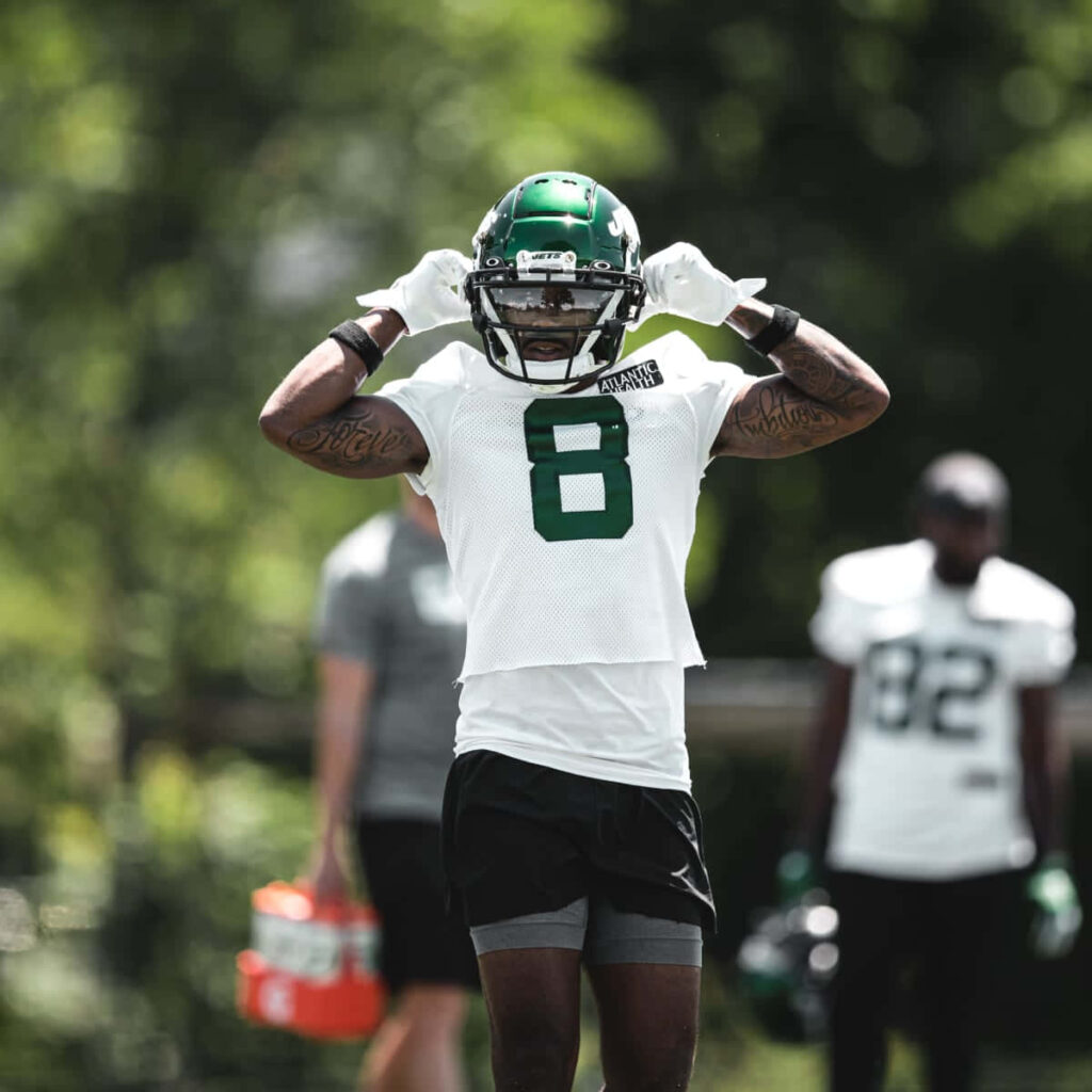 Elijah Moore number 8 in dynamic football training pose with vibrant green outdoor background Wallpaper