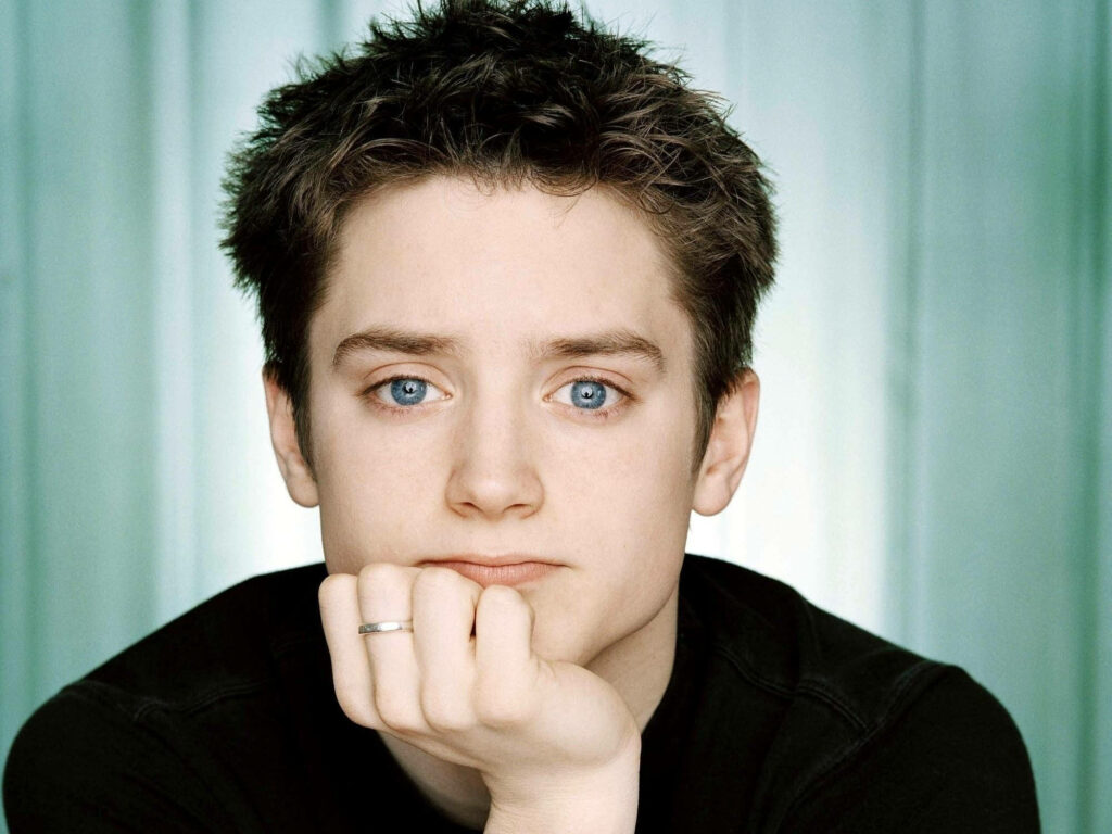 Elijah Wood close-up portrait with expressive blue eyes calm thoughtful expression studio lighting Wallpaper