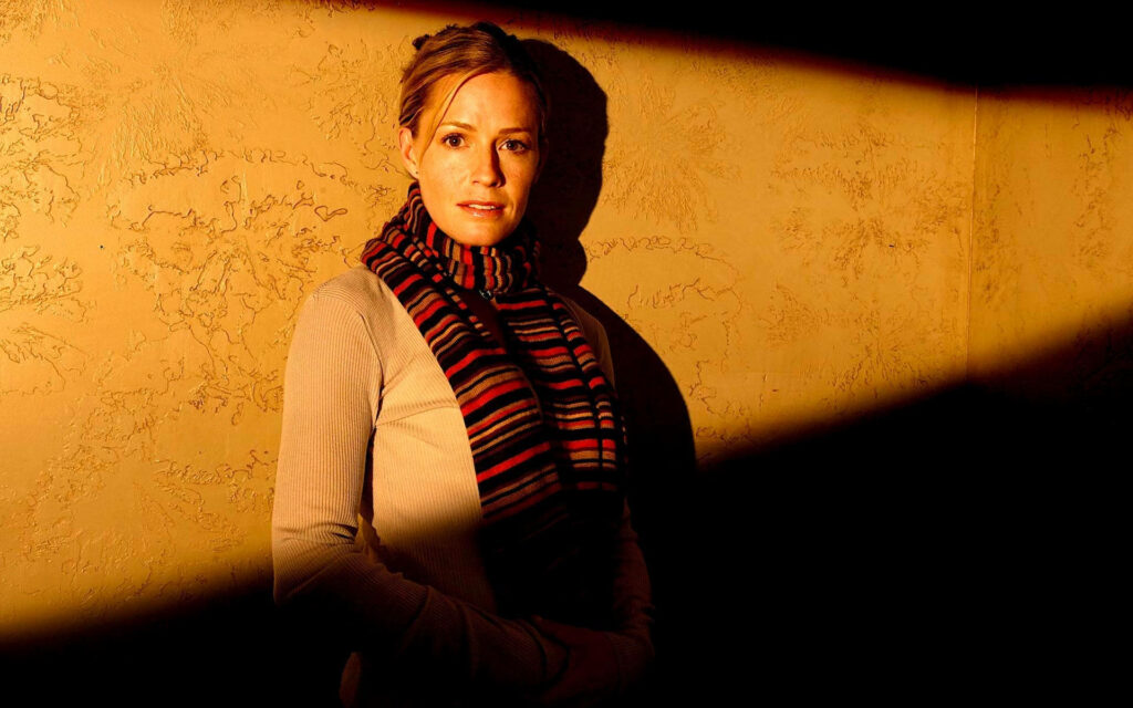 Elisabeth Shue portrait against golden textured wall with warm light striped scarf and neutral sweater Wallpaper