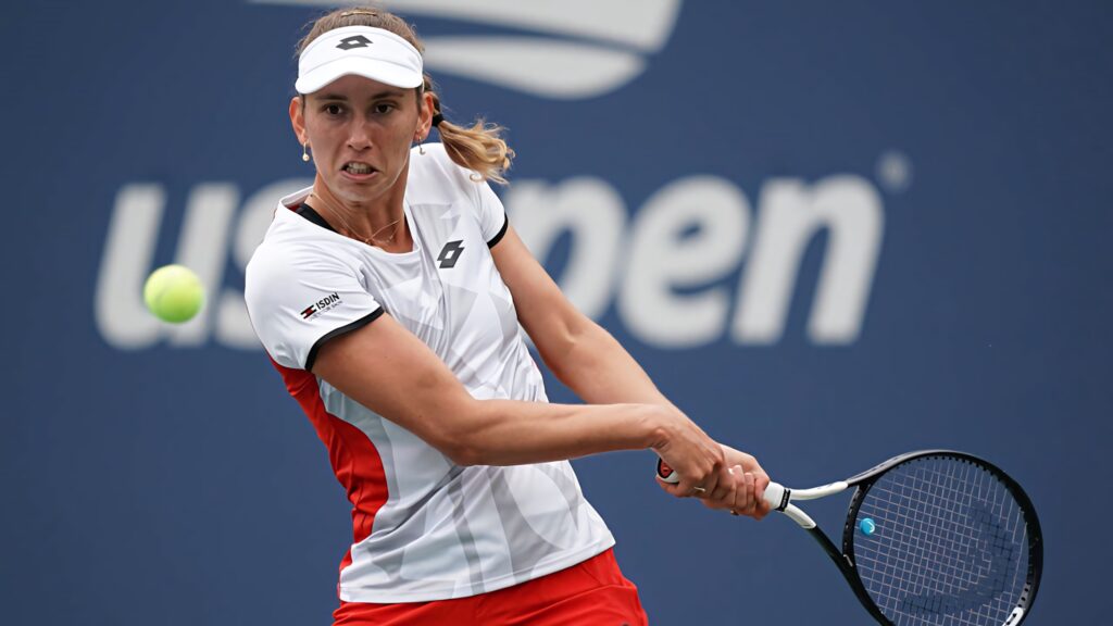 Elise Mertens powerful backhand shot at US Open on blue court showcasing athletic energy Wallpaper