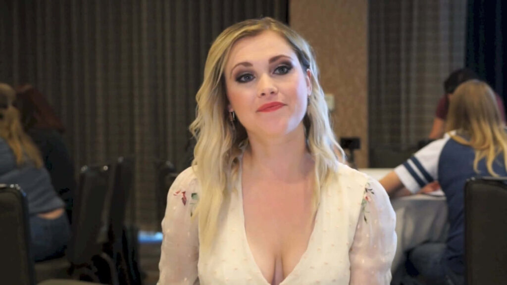 Eliza Taylor in floral blouse during softly lit interview in modern neutral toned room interior Wallpaper