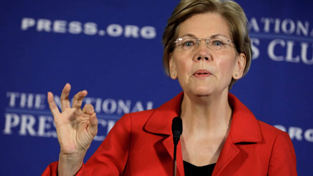 Elizabeth Warren speaking at press club in red blazer blue backdrop showing leadership and influence Wallpaper
