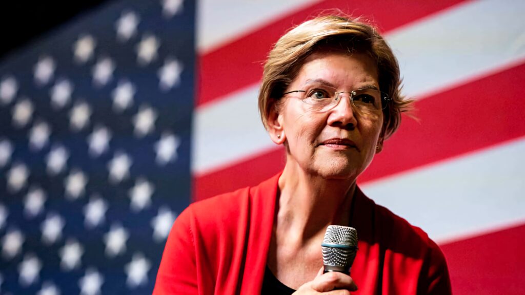 Elizabeth Warren holding microphone with American flag background vibrant patriotic wallpaper