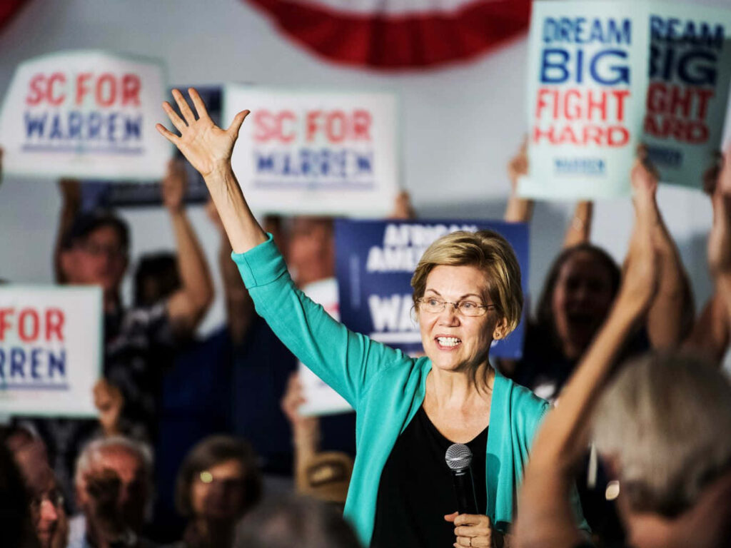Elizabeth Warren rally with enthusiastic supporters holding blue red signs in vibrant scene Wallpaper