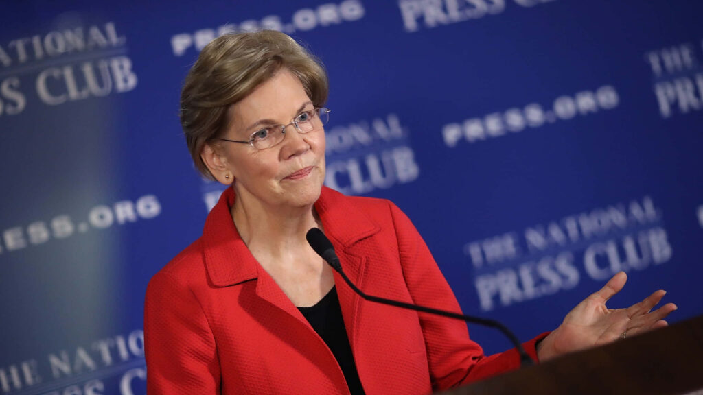 Elizabeth Warren delivers speech at National Press Club in red blazer against blue backdrop Wallpaper