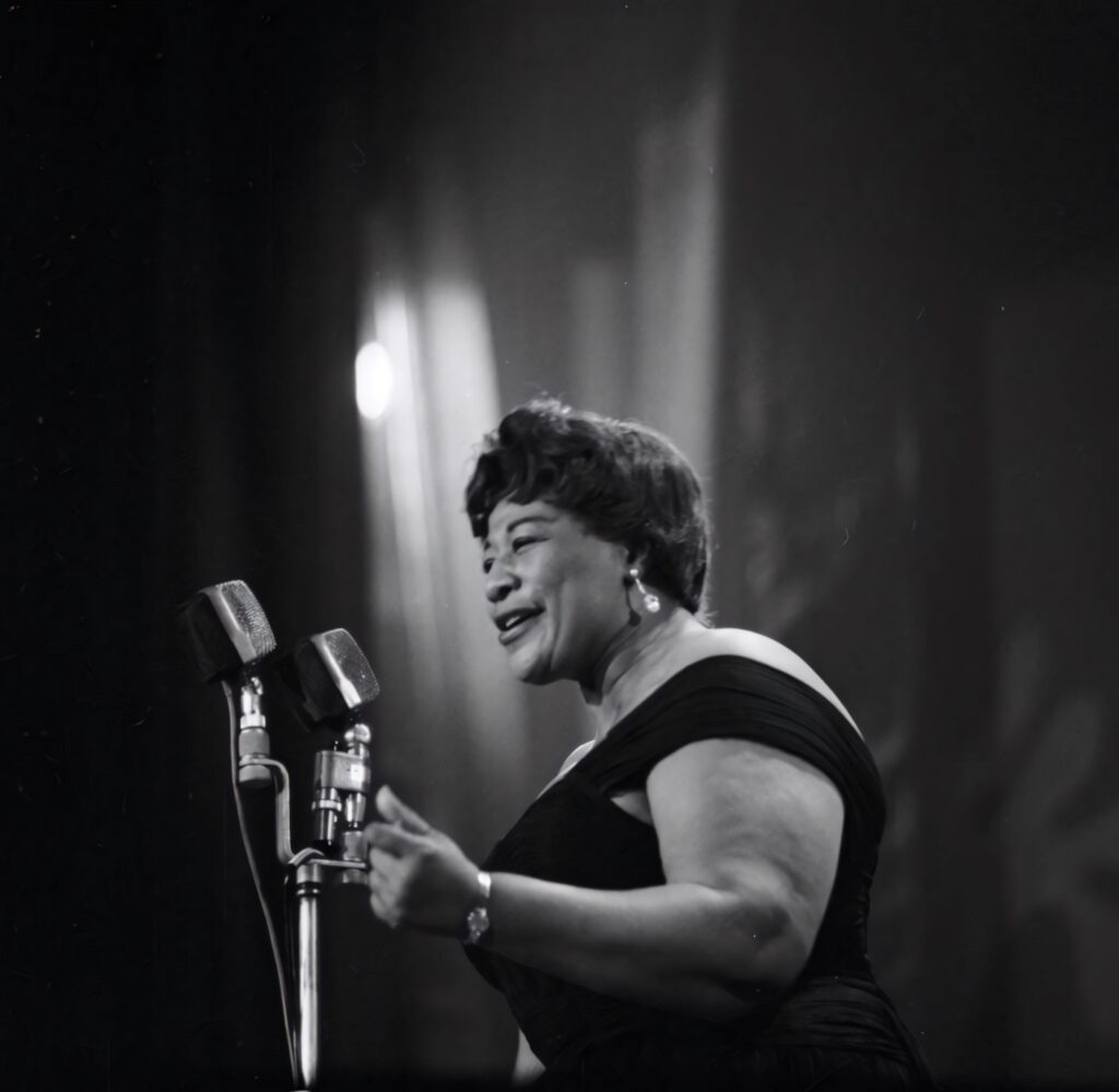 Ella Fitzgerald singing joyfully on stage with vintage microphones black and white wallpaper