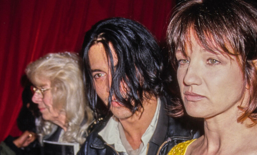 Ellen Barkin and Johnny Depp candid vintage portrait with moody red textured background wallpaper