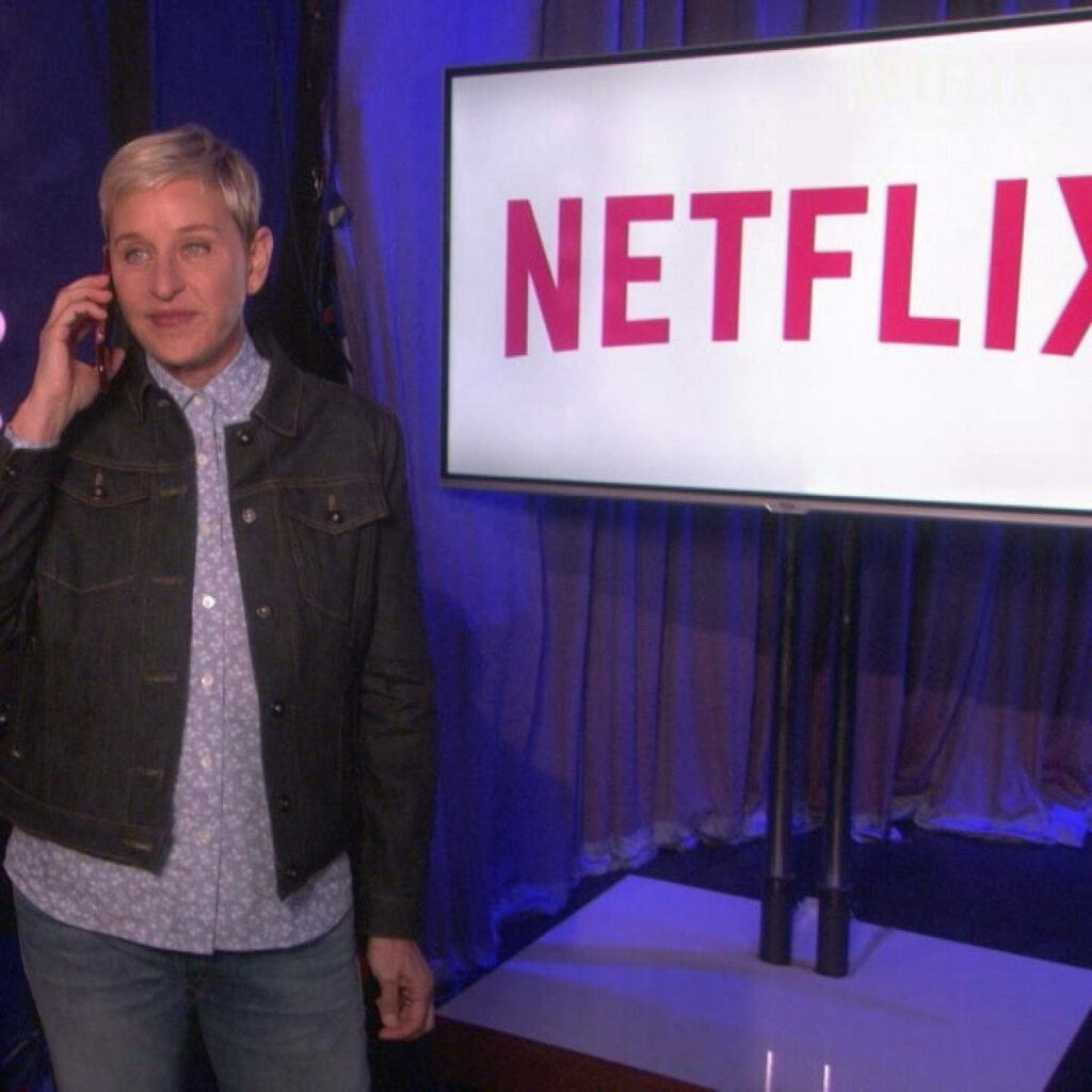Ellen DeGeneres on The Ellen Show standing by screen with Netflix logo promoting Netflix series Wallpaper
