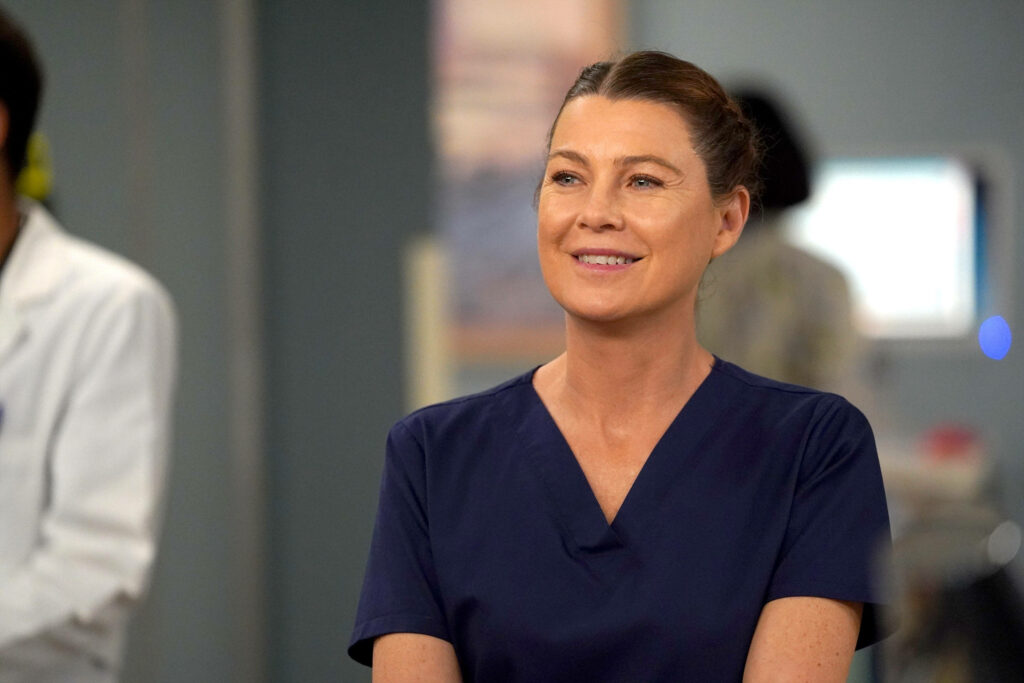 Ellen Pompeo in medical uniform smiling in hospital setting soft lighting cool tones medical drama Wallpaper