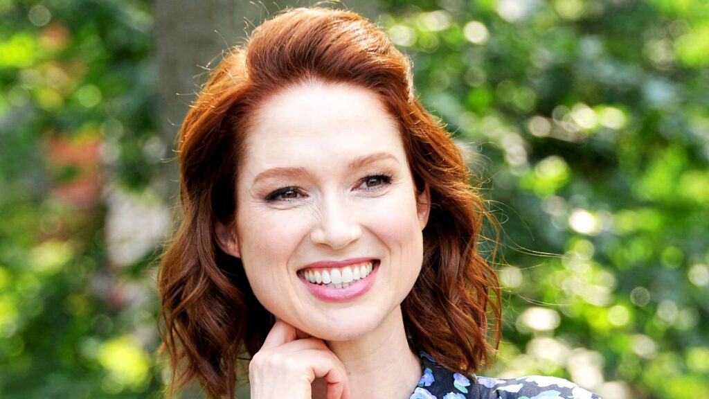 Ellie Kemper close-up outdoors vibrant green background radiant smile auburn hair natural makeup Wallpaper