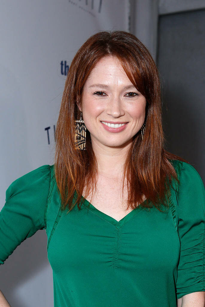 Ellie Kemper smiling in green top with geometric earrings and auburn hair on clean background Wallpaper
