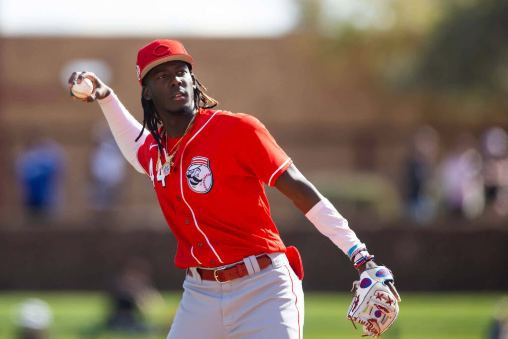 Elly De La Cruz in vibrant red Cincinnati Reds uniform showcasing focus and athleticism Wallpaper