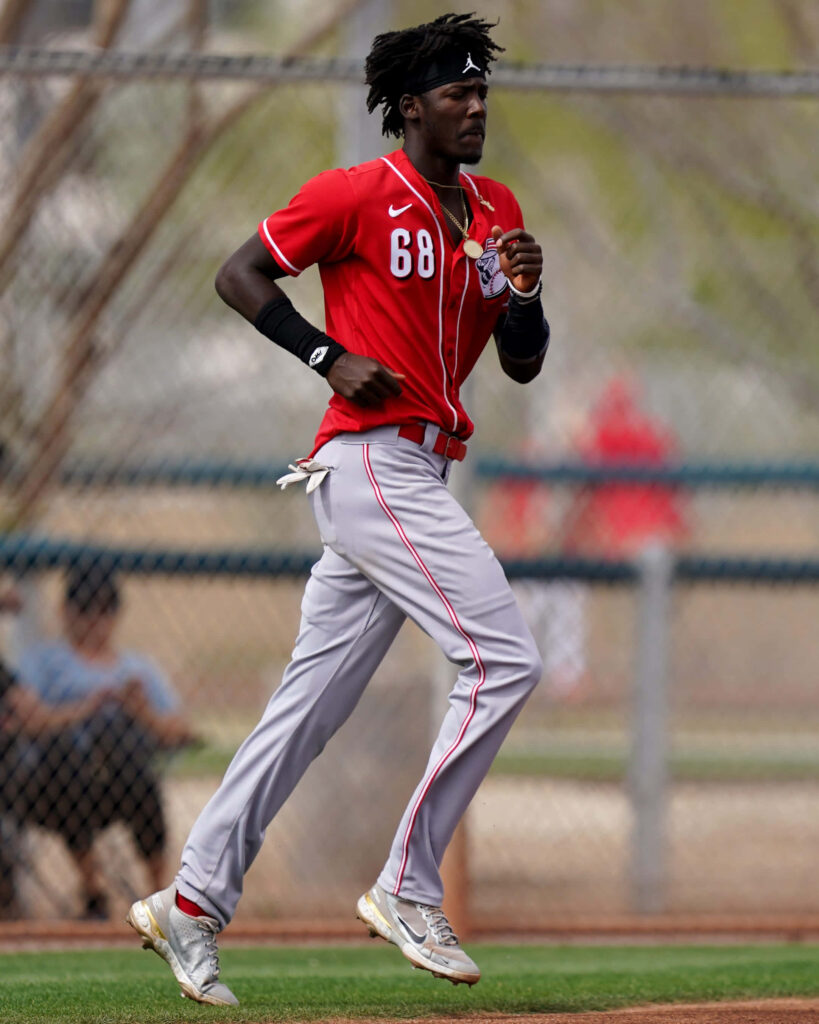 Elly De La Cruz running in Cincinnati Reds jersey number 68 on baseball field action shot Wallpaper