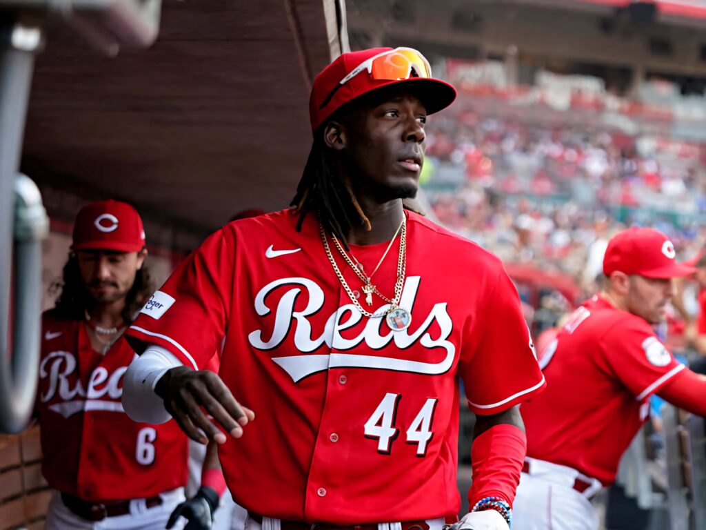 Elly De La Cruz in Reds uniform number 44 with gold chains in MLB dugout showcasing energy Wallpaper
