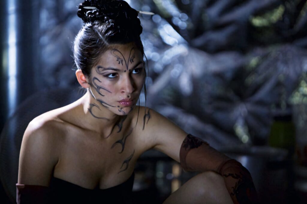 Elodie Yung with black body art and intense expression against metallic futuristic background wallpaper