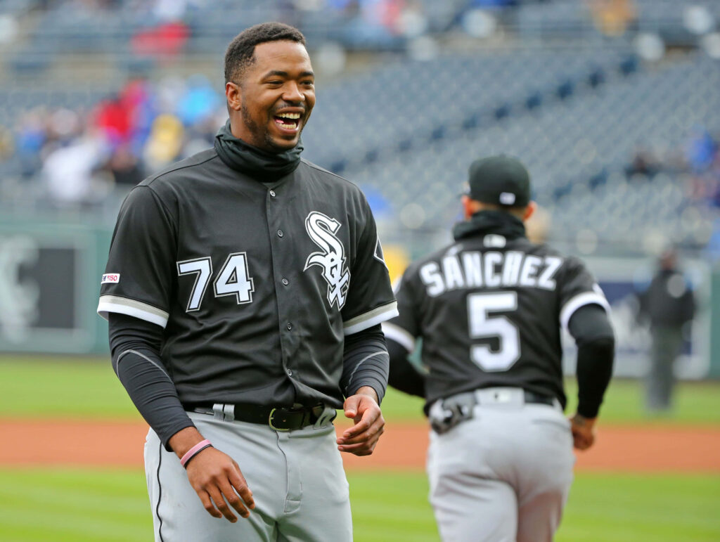 Eloy Jiménez in Chicago White Sox 74 uniform smiles on field with blurred Sanchez 5 pre-game moment Wallpaper