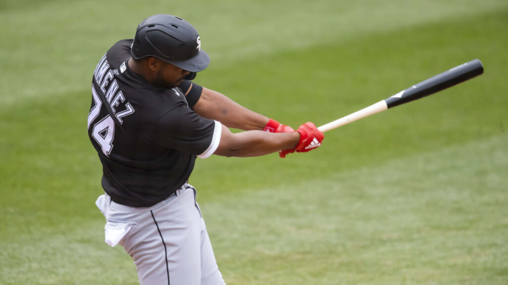 Eloy Jiménez mid swing in Chicago White Sox uniform on green field dynamic baseball wallpaper
